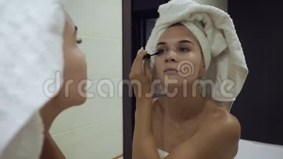 在浴室的睫毛上涂睫毛膏的年轻女人视频的预览图