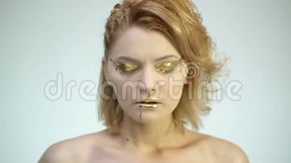 高级时装模特女子黄金化妆在工作室摆姿势美丽女孩的肖像时髦的金色皮肤视频的预览图