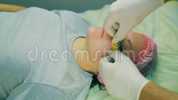 戴着手套的男性美容师的双手将胶原蛋白垫在眼睛下面贴在女人脸上视频的预览图