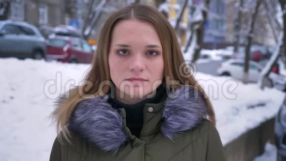 在一个下雪的日子里穿着冬衣站在户外的年轻白种人深色头发的女性特写镜头视频的预览图