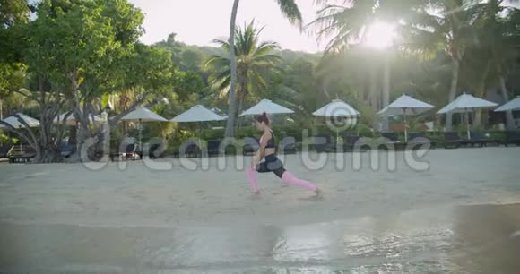 慢动作漂亮的年轻女子在沙滩上练习瑜伽外面的运动女孩视频的预览图