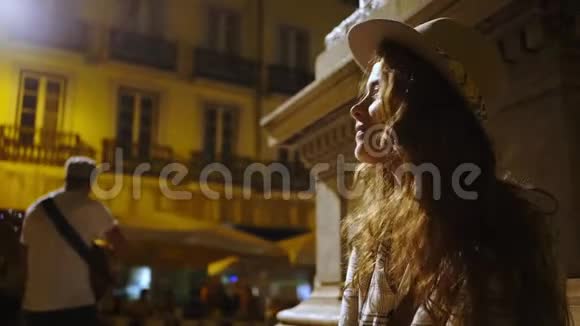 一位在夜间聆听街头音乐家的肖像女子视频的预览图