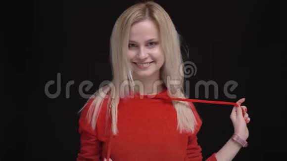 年轻的白发白种人白种人穿着红色毛衣的白种人女孩的肖像调情地把头发摇进相机旋转着视频的预览图