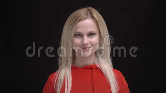 年轻的白发白种人白种人的肖像穿着红色毛衣颤抖着头发谦卑地在黑色镜头中微笑视频的预览图