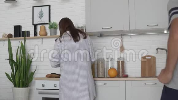 睡衣的年轻女子早上在厨房准备早餐视频的预览图