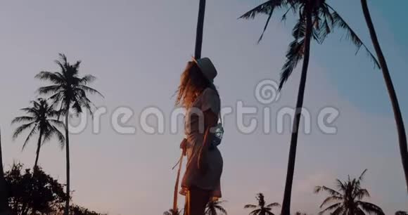 穿着连衣裙戴着帽子在热带海滩放松视频的预览图