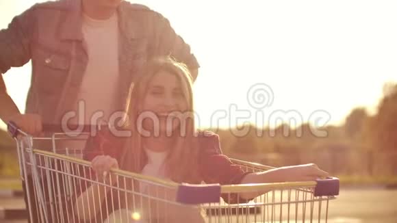 一对夫妇在户外停车场上骑着购物车年轻时尚的小跑车与购物车一起享受乐趣视频的预览图