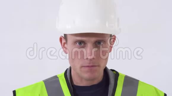 一个穿着建筑工服戴着头盔的自信杀手的肖像在摄影棚拍摄的白色背景视频的预览图