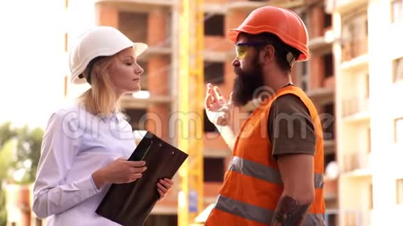 男女土木工程师在施工现场交谈建筑中的男女建筑工人视频的预览图