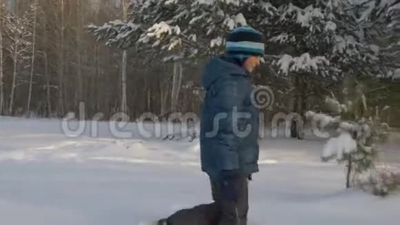 快乐少年走过冬天森林里的雪堆冬季活动视频的预览图