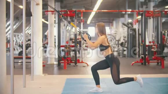一位在健身房训练的女运动员握住手柄膝盖向下做视频的预览图