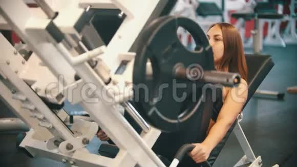 在体育馆训练的女运动员在训练器械上做腿部按压视频的预览图