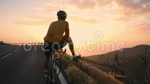 骑自行车的人穿着黄色的t恤在山上看日落健身后休息钢铁侠视频的预览图