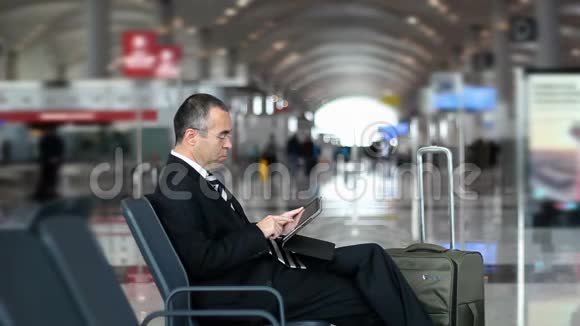 在机场使用平板电脑的商务旅客视频的预览图