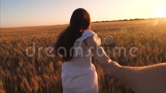 女孩跑过田野小麦牵着一个男人手在夕阳的照耀下笑着慢动作视频的预览图
