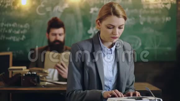 穿西装的女人在学校董事会背景下用打字机打字男人在看书智能人工作视频的预览图