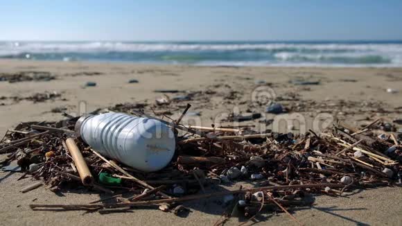 海浪运动背景下海滩生态系统塑料瓶垃圾4k视频的预览图