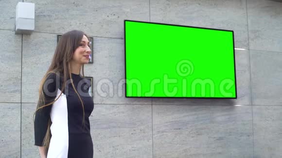 年轻的微笑商务女性在绿色大屏幕上做演讲视频的预览图