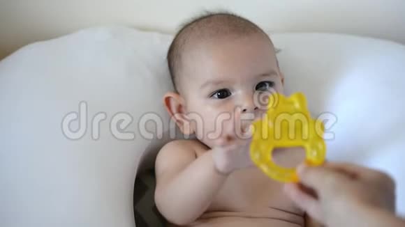 可爱的婴儿带着黄色的牙齿环可爱的婴儿肖像视频的预览图