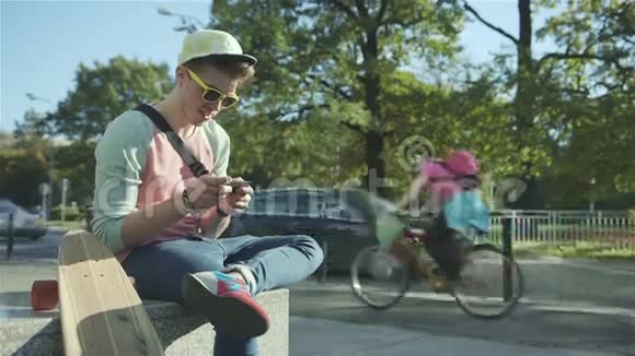 一个城市里有滑板的年轻人用手机发短信视频的预览图