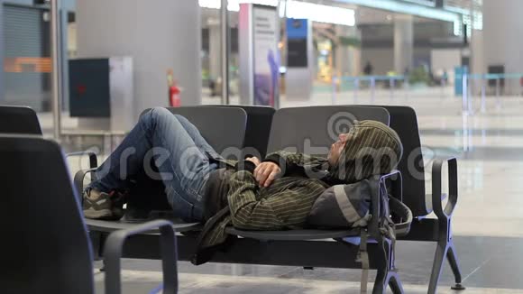 旅客青年在机场候机楼等候飞机时睡觉视频的预览图