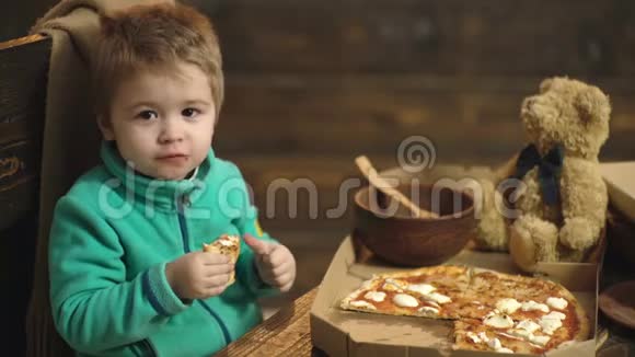 把吃披萨的可爱小男孩关起来男孩吃美味的披萨木制背景的美味意大利披萨视频的预览图
