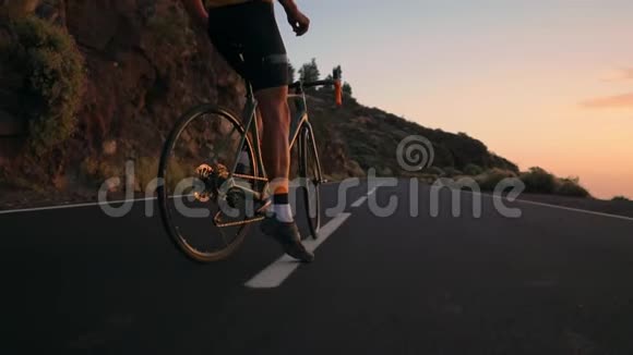 骑自行车的人穿着黄色t恤在公路上日落时分骑着山地车视频的预览图