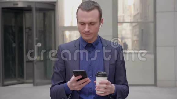 一个耳朵里有无线耳机的年轻商人正在智能手机上写一条信息视频的预览图
