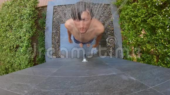 一个在热带花园洗澡的年轻人的慢镜头在热带度假胜地度假的概念青年视频的预览图