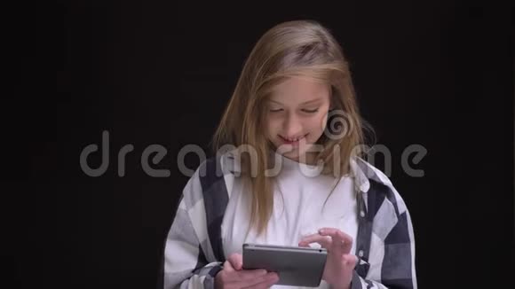穿着格子衬衫的金发白种人女孩微笑着用平板电脑工作高兴地看着镜头视频的预览图