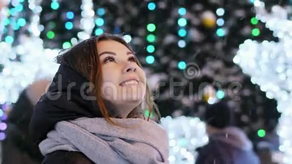 为圣诞节和新年装饰的夜晚城市美丽的年轻女子看雪视频的预览图