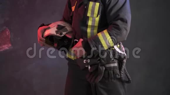 一名穿着特殊制服的勇敢消防员手持防护头盔站在灰色的墙壁上视频的预览图