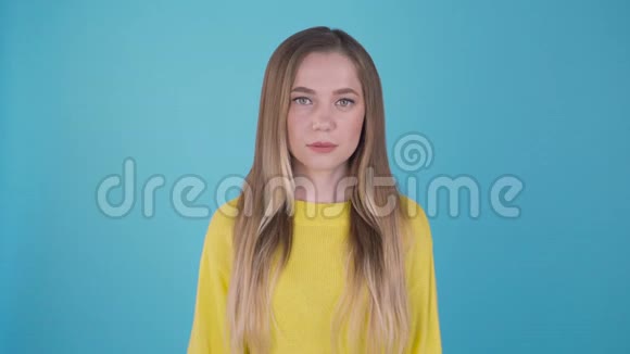 年轻美丽可爱开朗的女孩微笑着看着蓝色背景上的相机的肖像4K视频的预览图