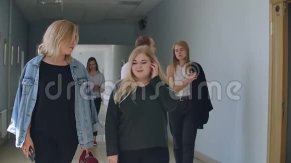一群学生沿着大学学校学院的走廊走着交流交谈和微笑一大片视频的预览图