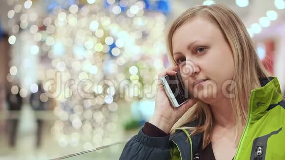 女人在智能手机上说话尴尬而害羞4她正站在商场的一个灯泡下视频的预览图