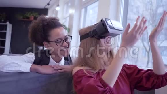 现代混血朋友快乐的非裔美国少女与白种人女友进入虚拟虚拟现实头盔游戏视频的预览图