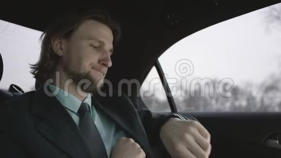 漂亮的男人棕色头发穿着开心果衬衫穿着灰色西装坐在车里付钱兜风视频的预览图