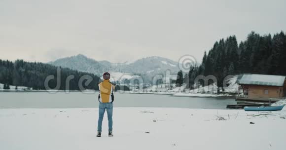 译文年轻的游客欣赏着冬天中带着白雪森林的湖光山色他是视频的预览图