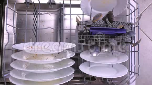 男人手把一个白色的脏盘子放进洗碗机的篮子里视频的预览图