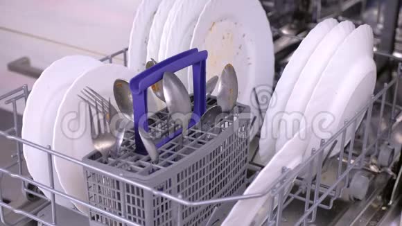 男人手在洗碗机里放一个白色的脏盘子然后在厨房里运行视频的预览图