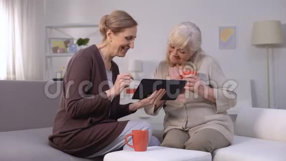 快乐的成熟女性在平板电脑上滚动网页微笑购物应用程序视频的预览图