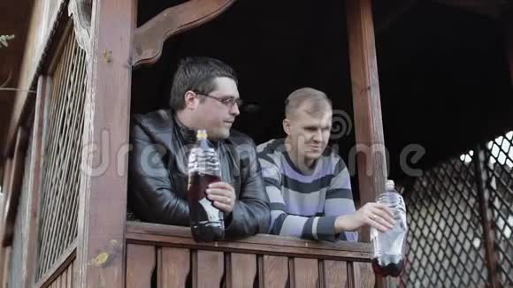 两个男人在露台上喝塑料瓶的啤酒视频的预览图
