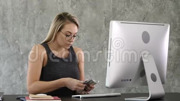 年轻女子坐在办公室里数钱视频的预览图