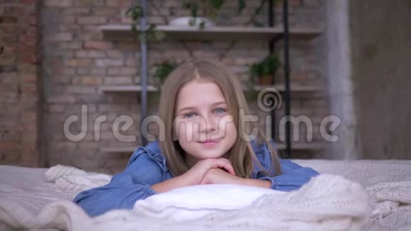 可爱的女孩子的肖像蓝眼睛躺在房间的枕头上视频的预览图