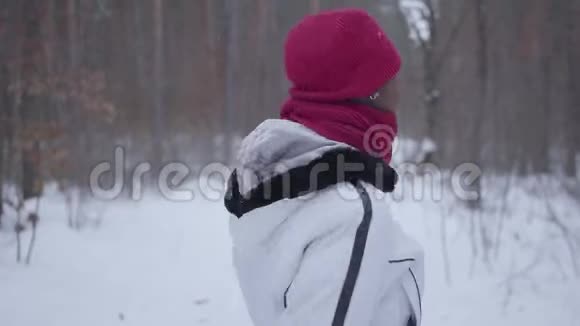 非裔美国女孩转身开始穿过冬季森林一个穿暖和夹克的美丽女孩独自在野外视频的预览图
