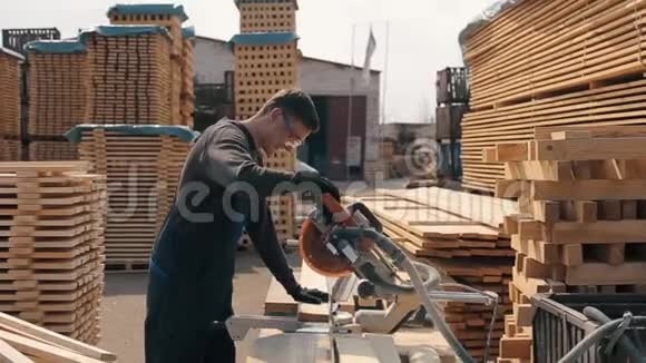 成年木工工人佩戴施工护目镜使用木切割机人切木木板视频的预览图