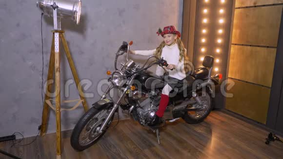 坐在摩托车上的戴帽子的漂亮少女的摄影棚画像视频的预览图