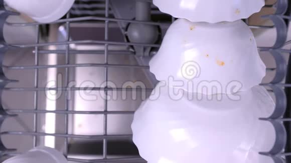 男人手把一个白色的脏杯和玻璃放在洗碗机的上篮里用厨房用具推着它视频的预览图