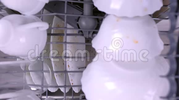 男人手把一个白色的脏盘子放进洗碗机里用厨房用具推篮子视频的预览图