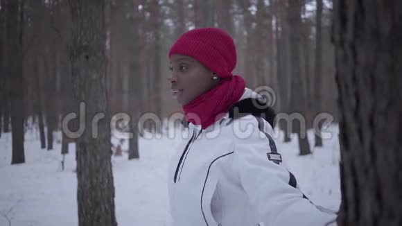 美国黑人女孩站在冬天的森林里然后转过身用手在树上环顾四周漂亮姑娘视频的预览图